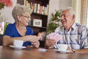 a smiling senior couple playing cards and having coffee